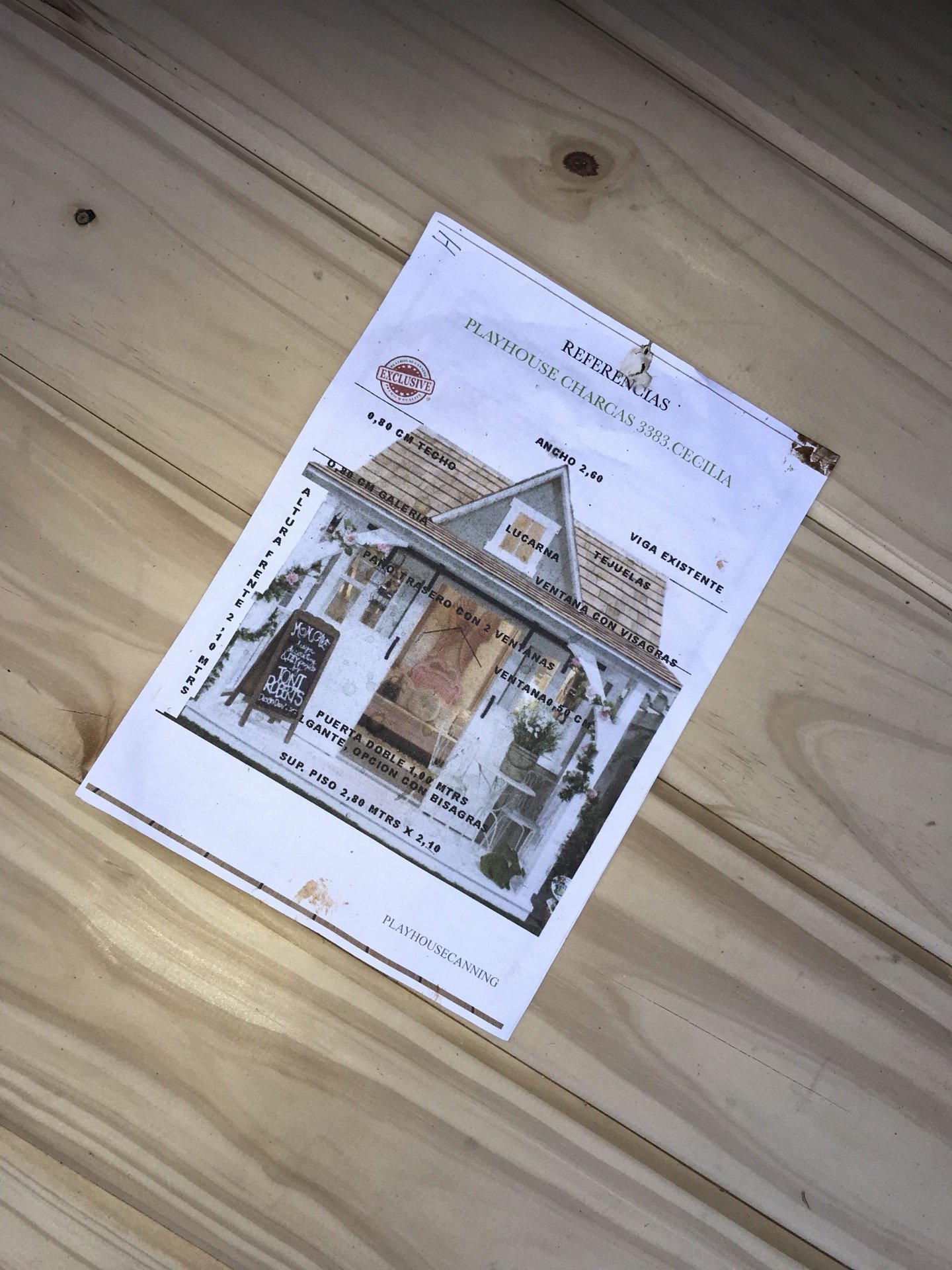 Plano técnico impreso de una casita, apoyado sobre la madera del taller