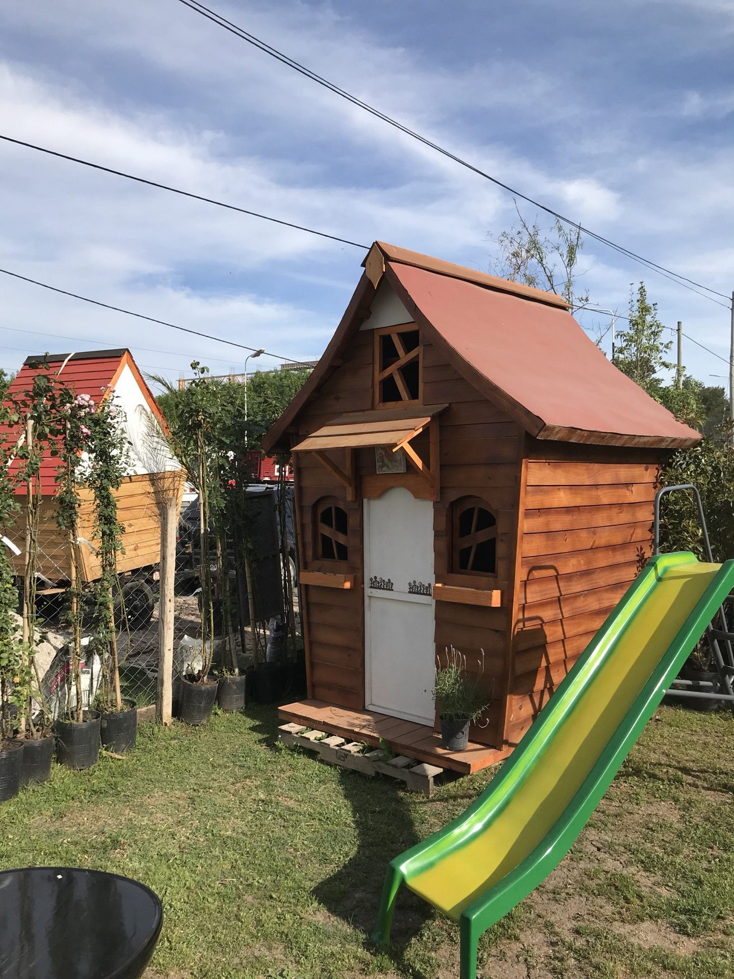 Casita con techo rojo y tobogán en el jardín