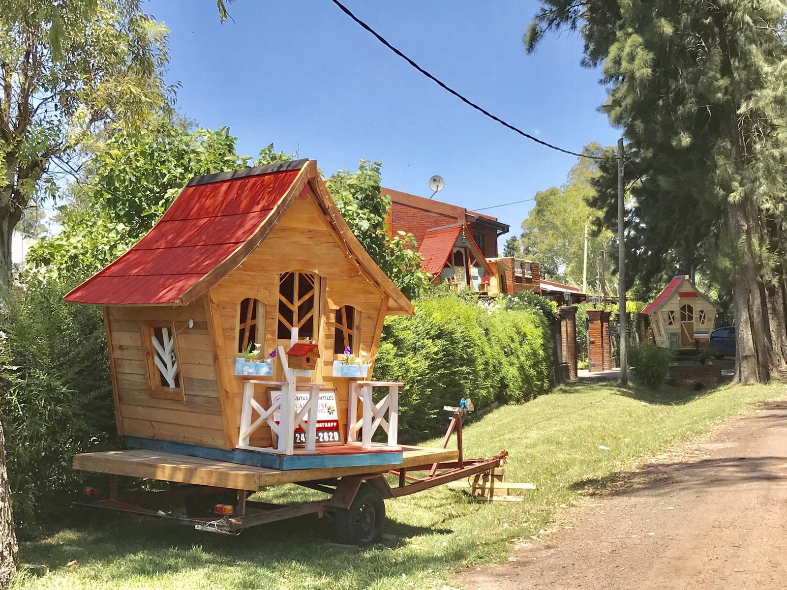 Casita de diseño con techo rojo en un jardín frondoso a la hora dorada